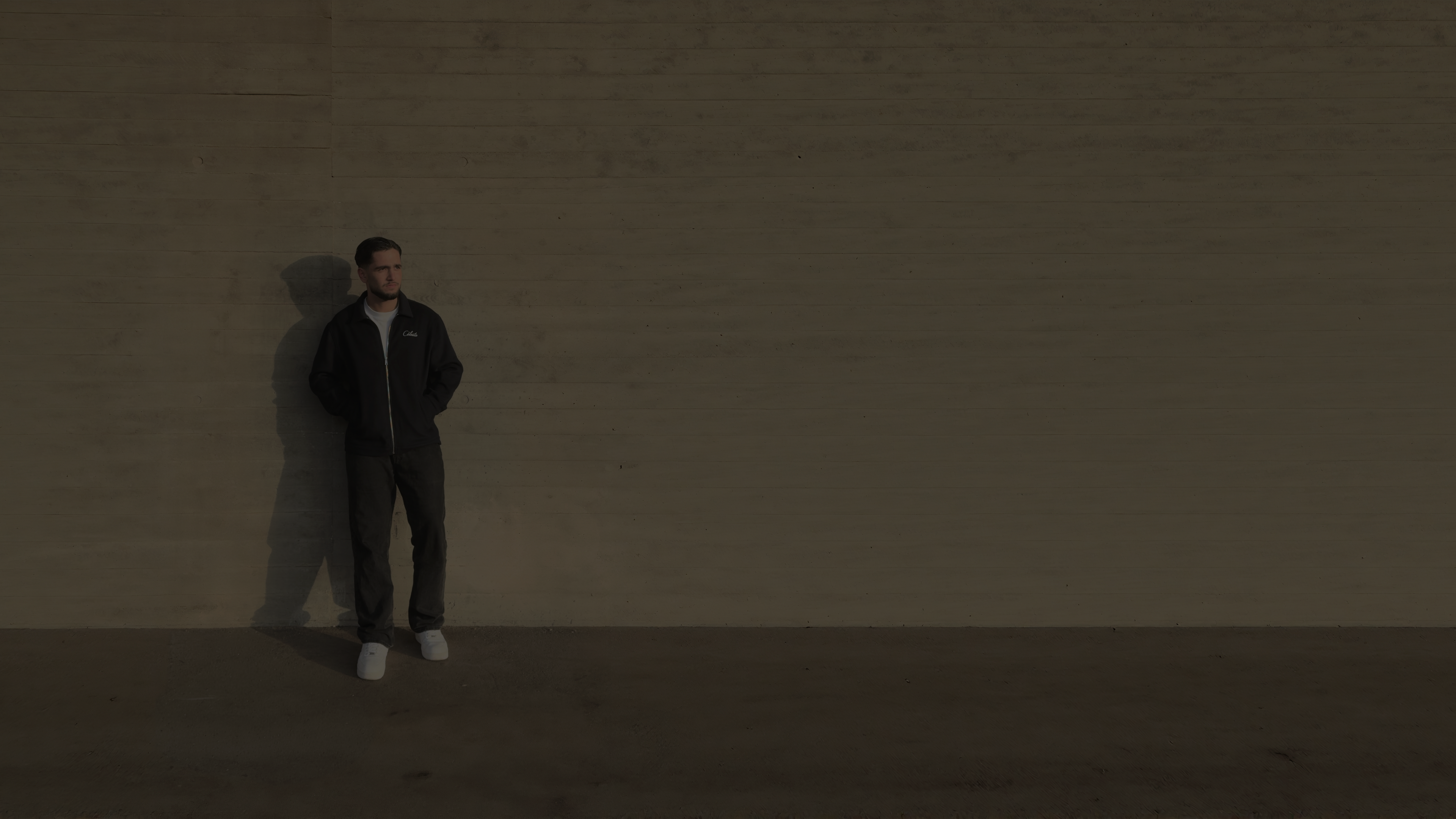 Person standing against a plain wall with a minimalistic background